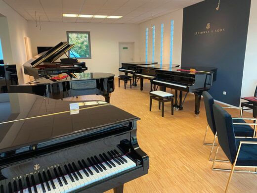 Ausstellung von Piano Hoffmann mit Flügeln vor der Steinway-&-Sons-Wand