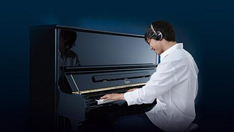 Pianist spielt mit Kopfhörern auf einem Klavier mit Stummschaltung